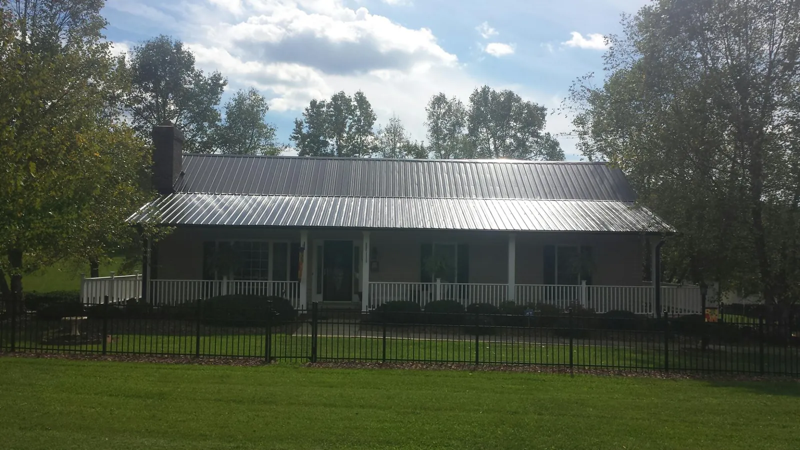 Gray metal roof on a brick ranch with a full width front porch — Gutter Guard Installation work by our crew in Odessa